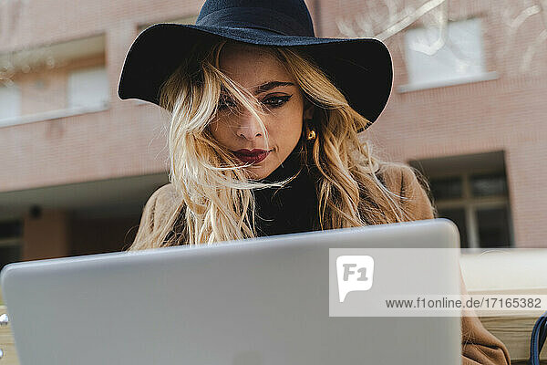 Young woman in hat using laptop