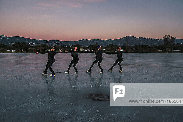 Female figure skaters practicing on frozen lake at dusk