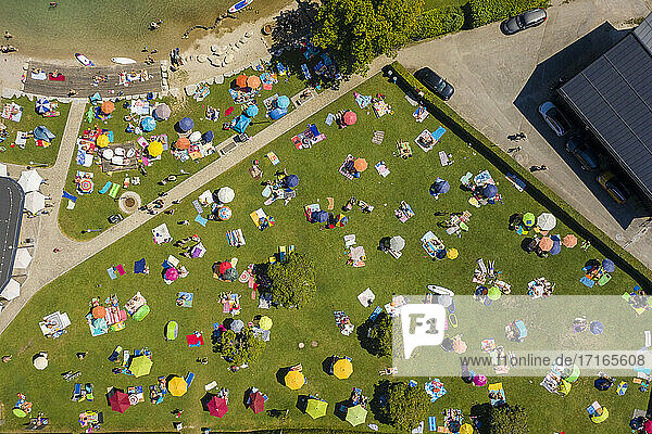 Österreich  Salzburg  Sankt Gilgen  Luftaufnahme einer großen Gruppe von Menschen beim Sonnenbaden auf einer grünen Wiese im Sommer