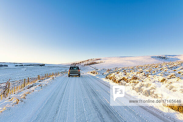 Vereinigtes Königreich  Schottland  East Lothian  Wintersonnenaufgang über einer Straße durch eine ländliche Landschaft