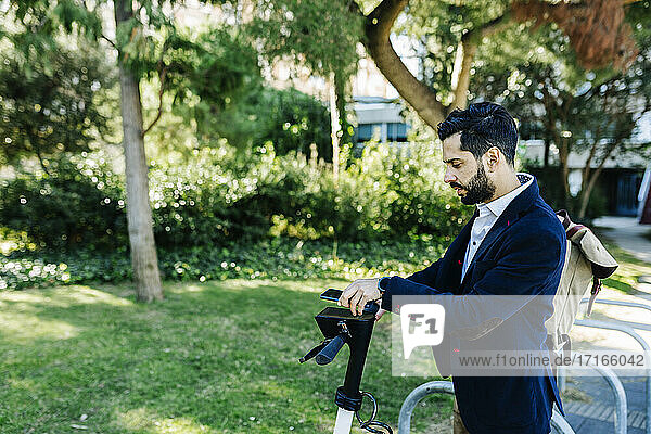 Businessman using mobile phone while standing at bicycle station