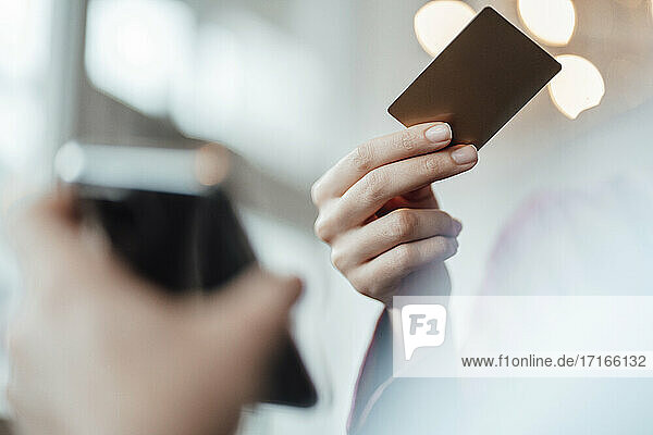 Die Hand einer Geschäftsfrau  die mit einer Kreditkarte an einen männlichen Kellner in einem Café bezahlt