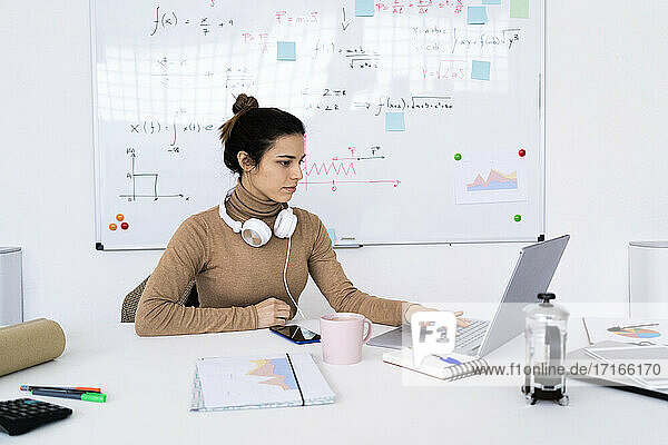 Junge Studentin mit Kopfhörern beim Lernen am Laptop