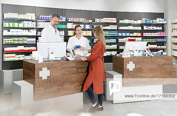 Female customer purchasing medicine from pharmacists in store