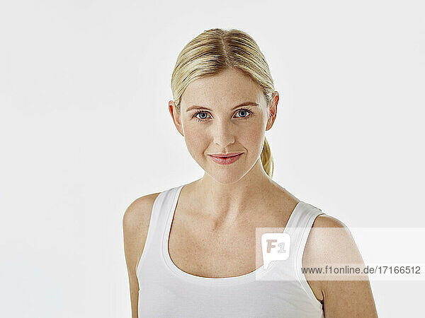 Smiling woman staring while standing against white background
