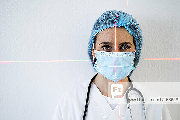 Weiblicher Arzt mit Laserlicht im Gesicht an der Wand