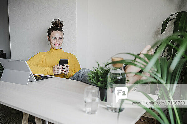 Young woman smiling while using mobile phone resting at home