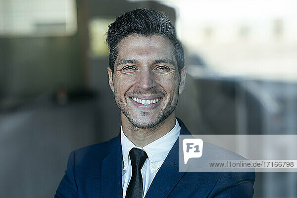 Confident businessman smiling while standing in office