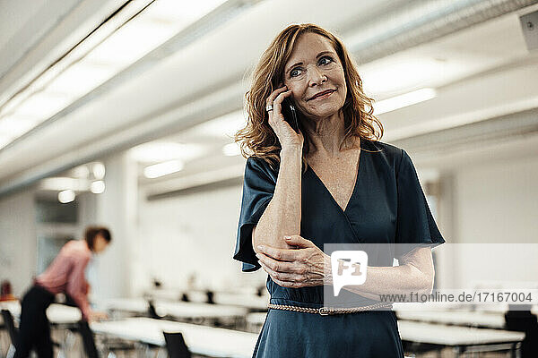 Weibliche Unternehmerin  die im Sitzungssaal im Büro mit einem Smartphone spricht