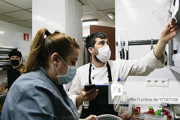 Koch und Köchin bei der Arbeit in der Großküche während COVID-19