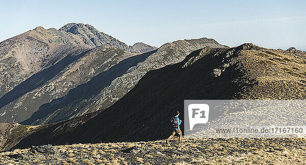 Male explorer running while trekking in mountain on sunny day