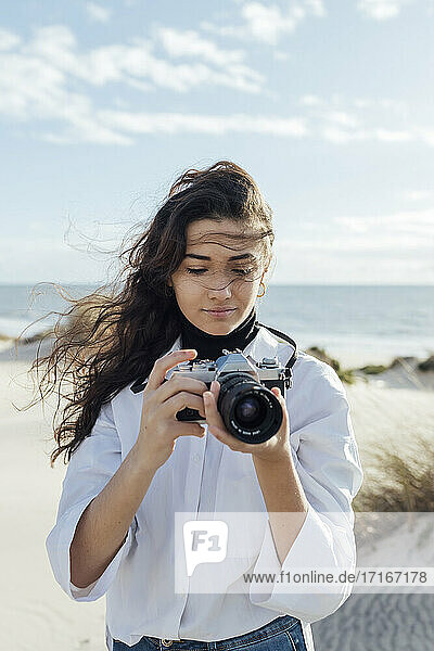 Young woman with vintage camera at beach during sunny day
