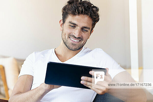 Mid adult man using digital tablet while sitting at home