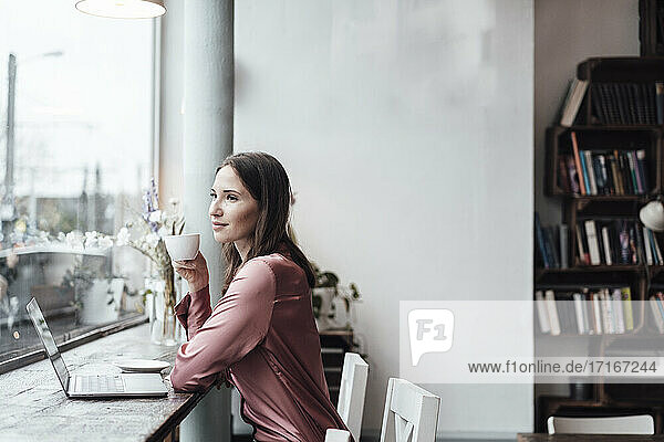 Geschäftsfrau trinkt Kaffee am Tisch  während sie im Cafe sitzt