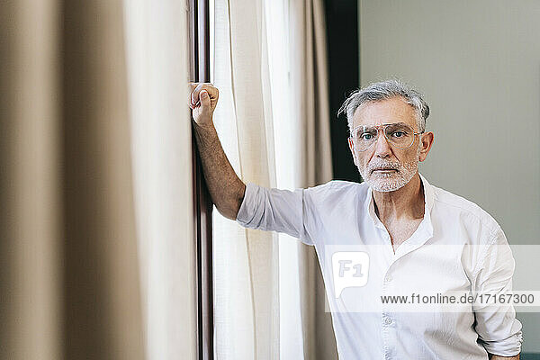 Mature man standing by window in hotel room