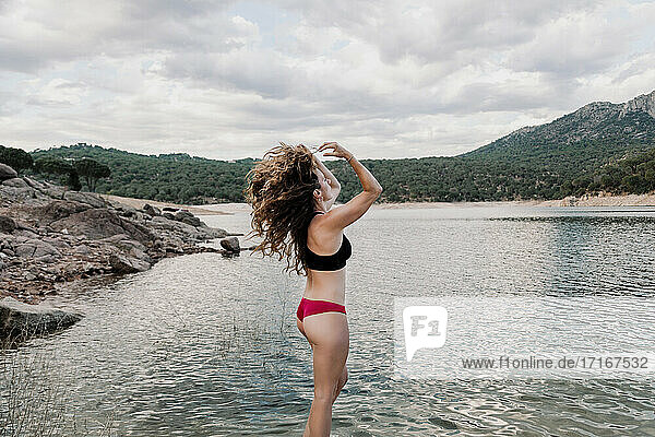 Frau wirft langes Haar  während sie am See steht