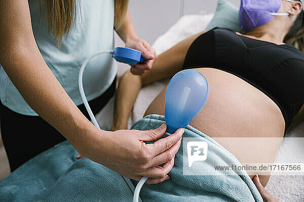 Midwife holding blue balloon against pregnant woman abdomen
