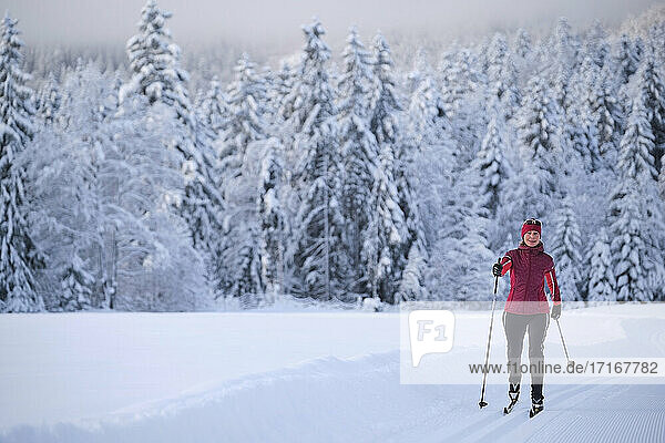 Frau in Warnkleidung beim Skifahren mit Skistock im Schnee