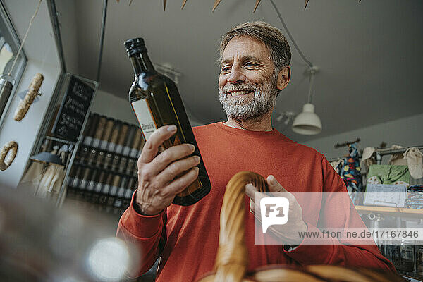 Smiling male customer holding drink bottle while shopping in zero waste store