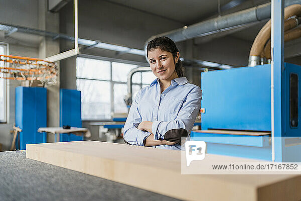 Smiling businesswoman with arms crossed standing at industry