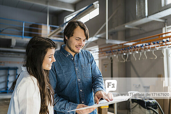 Smiling expertise pointing on file while working with colleague in industry