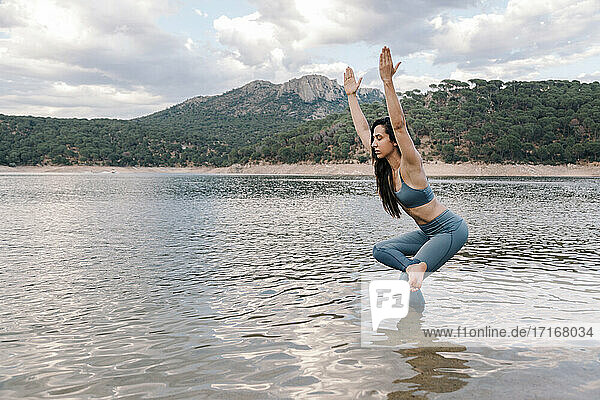 Junge Frau übt Yoga im See