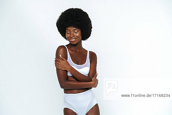Afro-American skinny woman wearing lingerie with arms crossed posing against white background