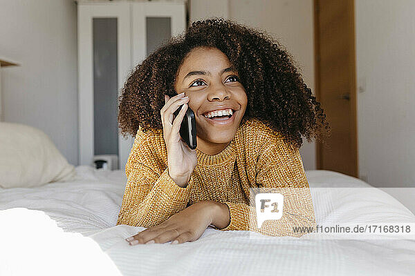 Smiling woman talking on mobile phone while resting at home