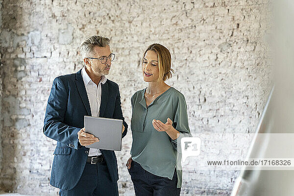 Geschäftsfrau im Gespräch mit einem Architekten bei der Arbeit an einem digitalen Tablet auf einer Baustelle