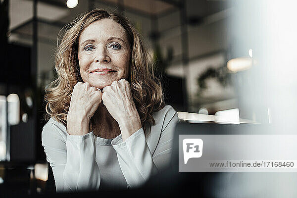 Smiling female entrepreneur with hand on chin in office