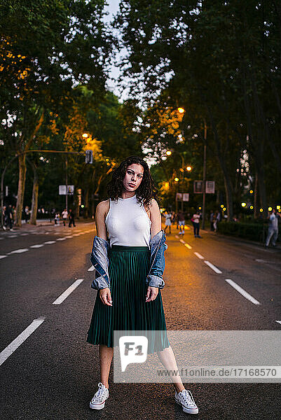 Schöne Frau in Jeansjacke posiert auf der Straße im Park in der Abenddämmerung