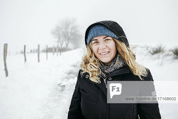 Blond woman standing on snow during vacations