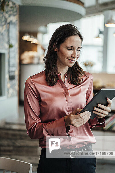 Lächelnde Geschäftsfrau mit digitalem Tablet in einem Café