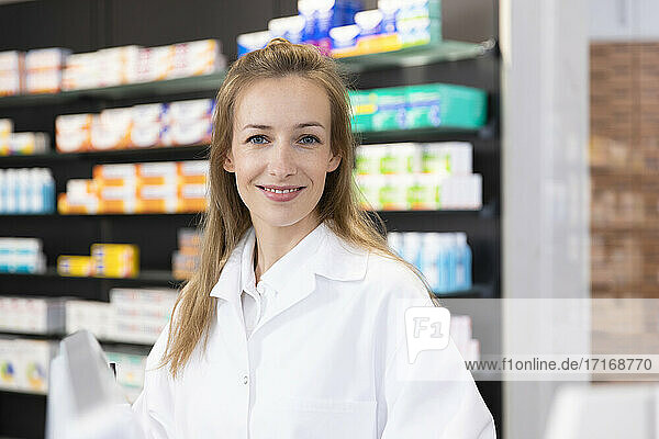 Smiling female pharmacist at checkout in store