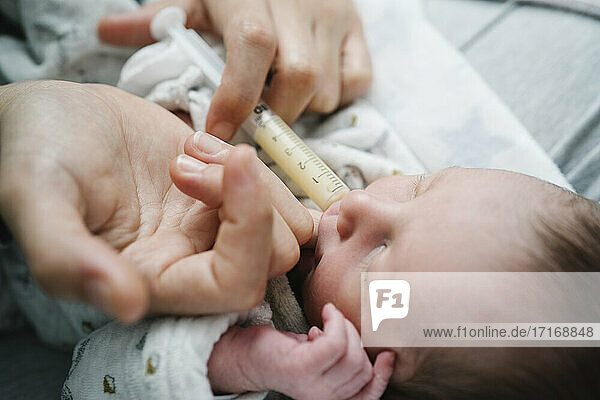 Frau füttert neugeborenen Jungen mit Spritze im Krankenhaus