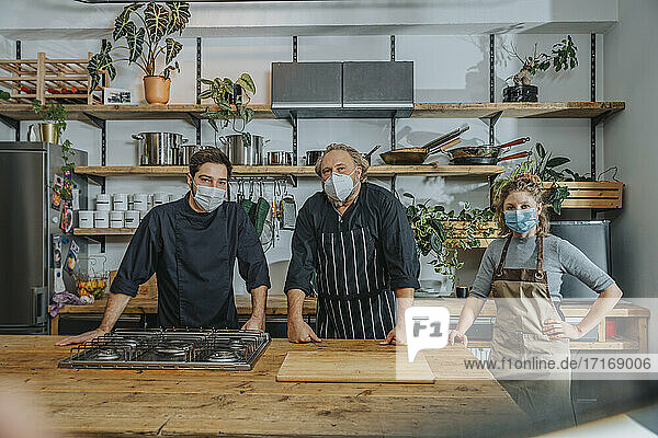 Chefs wearing protective face mask staring while standing in kitchen