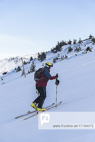Mature male skier climbing on snowy mountain