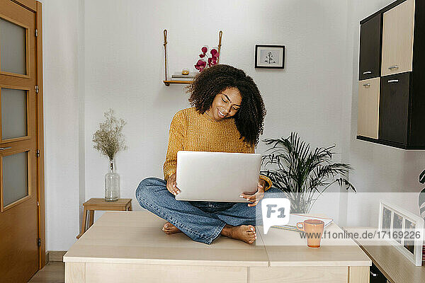 Young woman using laptop while sitting on table at home