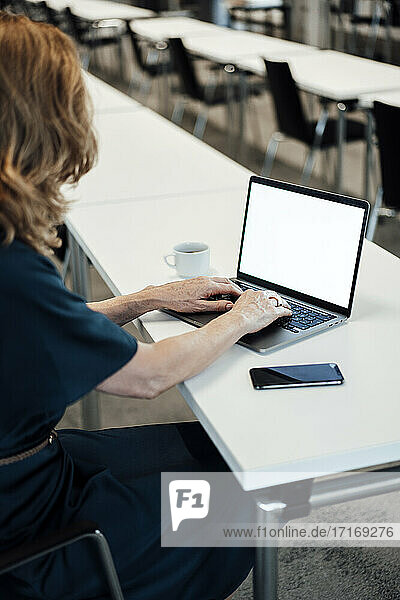 Unternehmerin tippt auf einem Laptop im Sitzungssaal eines Büros