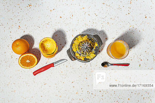 Orangensaft mit Saftpresse aus Edelstahl auf modernem Terrazzo-Marmor