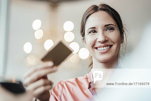 Smiling businesswoman holding credit card at cafe