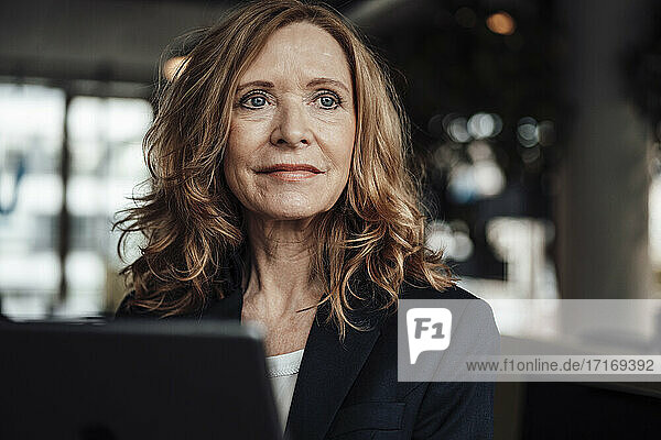 Geschäftsfrau mit digitalem Tablet  die im Büro wegschaut