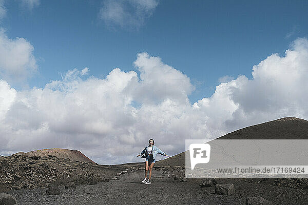 Woman with arms outstretched spinning while standing on footpath at Volcano El Cuervo  Lanzarote  Spain