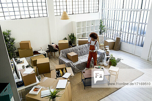 Afro-Frau steht inmitten von Kartons im Wohnzimmer ihres neuen Zuhauses