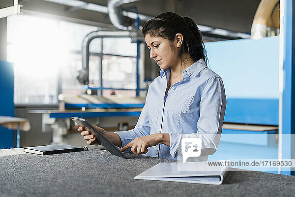 Female expertise using digital tablet while standing at industry