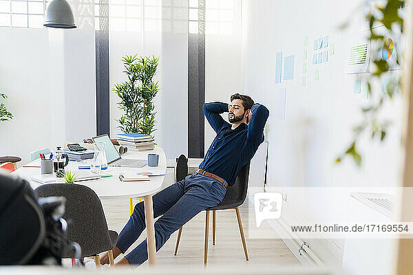 Relaxed male entrepreneur with eyes closed sitting in office