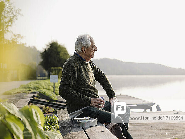 Älterer Mann  der auf einer Bank sitzend die Aussicht betrachtet