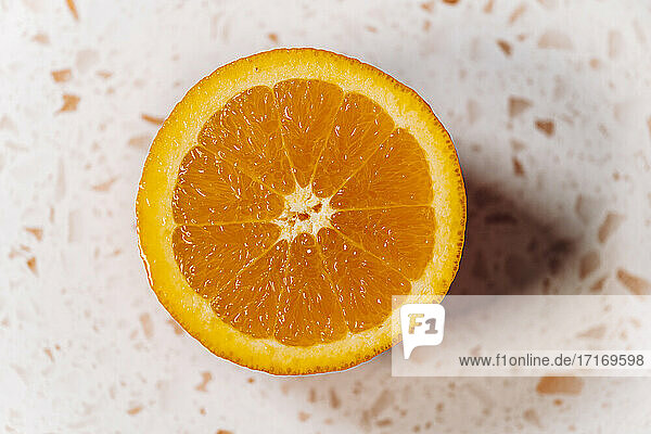 Halbe Orange in Nahaufnahme auf einem modernen Terrazzo-Marmor