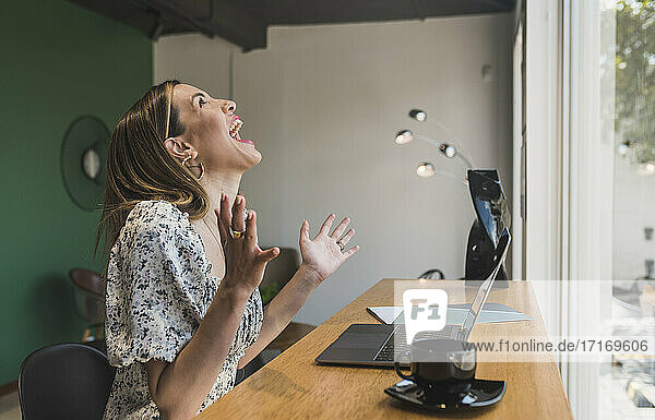 Businesswoman laughing while working at table in cafe