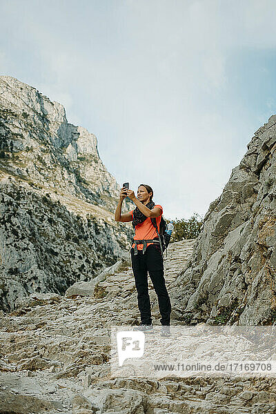Woman explorer using mobile phone while standing at Cares Trail in Picos De Europe National Park  Asturias  Spain